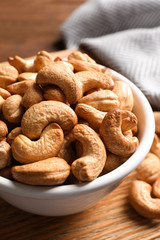Tasty cashew nuts in bowl on table, closeup