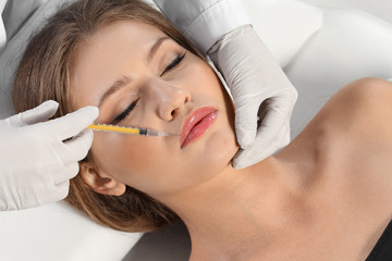 Young woman getting lips injection in clinic. Cosmetic surgery