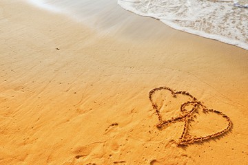 Valentine's Day concept, two heart shape writing on sand beach with waves ocean.