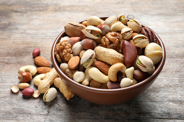 Bowl with mixed organic nuts on wooden background