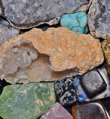 A selection of different semi-precious gemstones grouped together on a black table as seen from an...