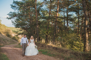 Happy wedding couple walks in nature. Loving young family is photographed on a wedding day. Wonderful                  emotions and feelings of amazing people. Photosession in Ukraine. Dnister
