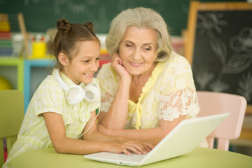 Portrait of grandmother and daughter using modern laptop