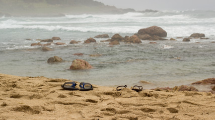 Fototapeta na wymiar two pairs of flip flops on the beach 