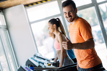 Healthy man and woman running on a treadmill in a gym