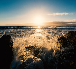 Splash against the rocks at sunset