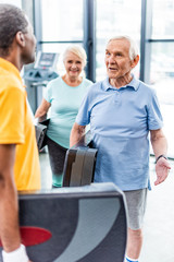 male senior sportsmen with step platforms talking to each other at gym