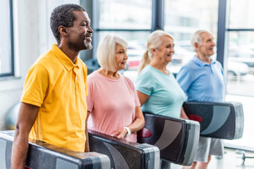 selective focus of multiethnic senior sportspeople holding step platforms at gym