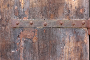 Old wooden door and metal hinge, background texture, worn brown aged tones