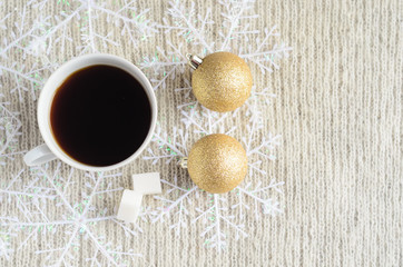 A Cup of coffee , decorated snowflakes and two pair Christmas golden balls on a light wool sweater.Winter concept.