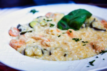 Tasty risotto with Shrimp, fresh herbs vegetables on a white plate