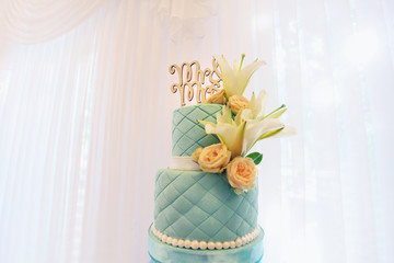 Beautiful wedding cake made of mastic, decorated with flowers, inscription Mr & Mrs., close-up