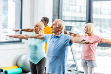 senior multiethnic athletes synchronous doing exercise at sports hall