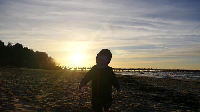 2 years old boy running forward on the sand silhouette outdoors