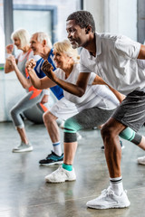 african american sportsman synchronous exercising with friends at sports hall