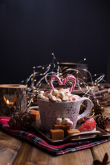 Cocoa with marshmallows in a white mug, different Christmas candies and sweets. Photo in dark style and free space for text. Candles and holiday decorations