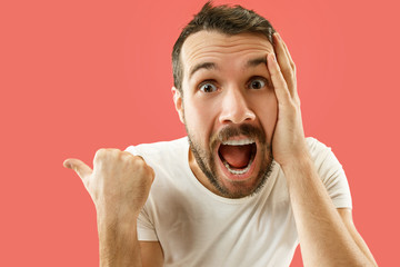 Wow. Attractive male half-length front portrait on coral studio backgroud. Young emotional...