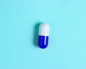 White blue pill capsule on a blue background. Minimalism, medical concept, top view.