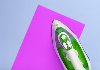 Iron for ironing on a colored pastel background, top view. Minimalism.