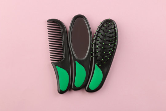 A set of different hair brushes and a mirror in one style on a bright pink background. view from above