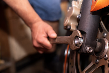 Obraz na płótnie Canvas Mechaniker repariert sein Motorrad mit einem Schraubenschlüssel