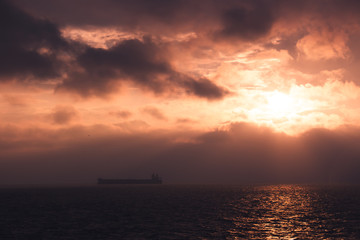 Naklejka na ściany i meble cargo ship outgoing from port at sunrise