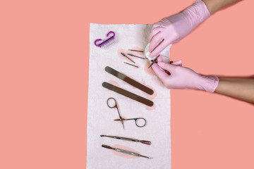 manicure and pedicure equipment. master nails in pink gloves holds manicure tool on the pink...