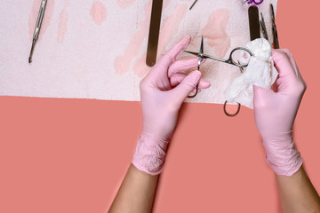 manicure and pedicure equipment. master nails in pink gloves holds manicure tool scissors on the...