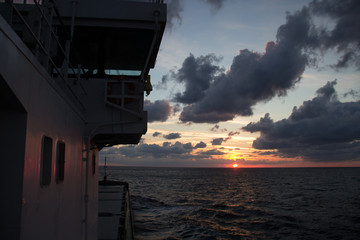 cargo ship outgoing from port at sunrise