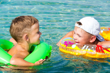 two happy children having fun in the water with inflateble ring