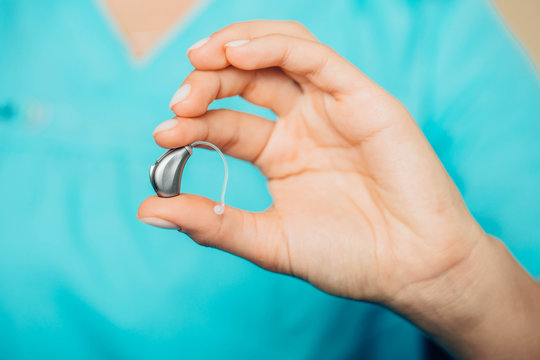Close-up of a doctors hand holding modern hearing aid for senior people