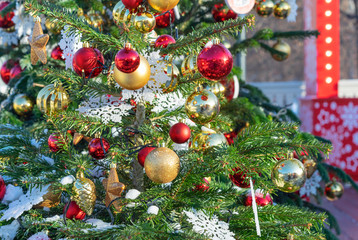 The Christmas tree is decorated with gold and red balls and white snowflakes.