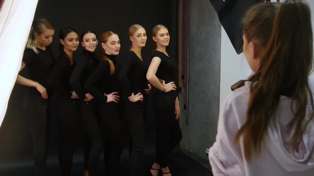 Young woman models having a photo session in the studio. Six different types of models in black clothes standing by each other and smiling for the camera