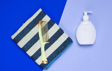 Bathroom accessories on a colored background. Towel, hairbrush, bottle shampoo. Hair care. Top view..