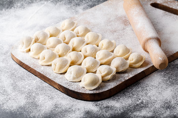 Homemade raw dumplings, pelmeni, on wooden background
