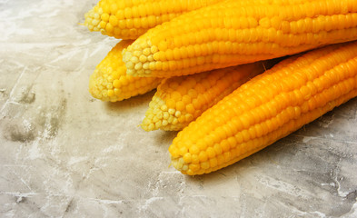Ripe boiled corn on a gray concrete table, top view.
