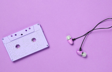 Audio cassette, headphones on purple background, music lover, minimalism, top view.