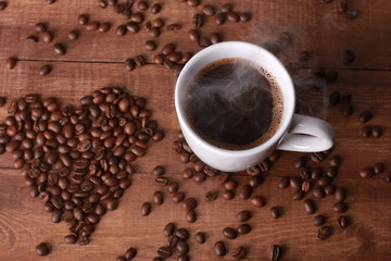 Steaming hot coffee and beans in shape of heart on vintage wooden table. Coffee break concept. White cup, Valentines day, espresso, top view