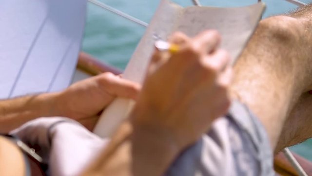 Sail boat navigating in the ocean sunny day showing the wooden parts and accessories compass and detail afternoon low wind man operating the ropes blue sky