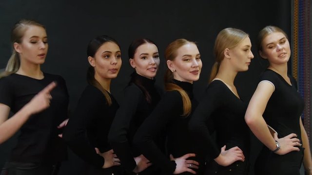 Young woman models having a photo session in the studio. Six different types of models standing by each other and smiling for the camera