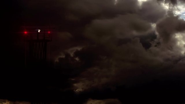 Storm Quickly Approaching to Airport. Communication tower with a rotating antenna and flashing signal lights against the background of rapidly changing weather at dusk
