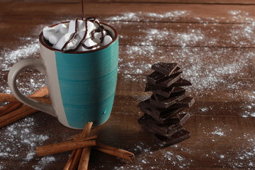 Cocoa, marshmallow, cinnamon sticks, pieces of chocolate and sugar powder on vintage wooden table. Sweets concept. Blue cup, winter drink, side view, confection