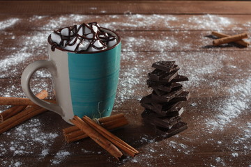 Cocoa, marshmallow, cinnamon sticks, pieces of chocolate and sugar powder on vintage wooden table. Desserts, sweets or coffee shop concept. Blue cup, winter drink, side view, confection