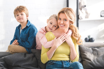 happy mother and cute little children spending time together and smiling at camera