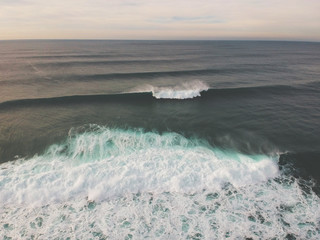 Aerial view from ocean waves in a surf spot at the sunset . Drone Photo.