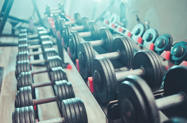  Close up many metal dumbbells on rack in sport fitness center.Highlight