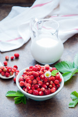 Breakfast with wild strawberries and milk on a brown background