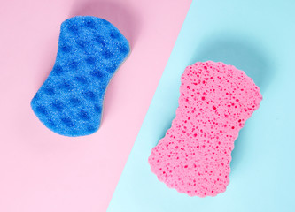 Two abrasive double-sided sponges on a pink-blue pastel background. Minimalism, top view
