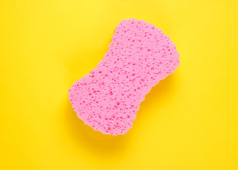 Soft pink bath sponge on a yellow background. Top view. Minimalism. .