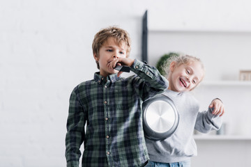 adorable siblings playing with remote controller and frying pan at home